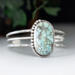 large oval turquoise with brown matrix natural stone bezel set accented with twisted wire and beads on a 3 wire stamped sterling silver cuff